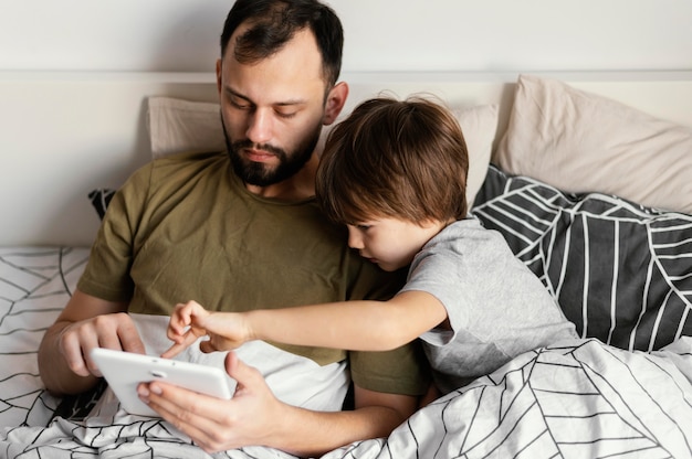 Padre e figlio del colpo medio a letto con il dispositivo