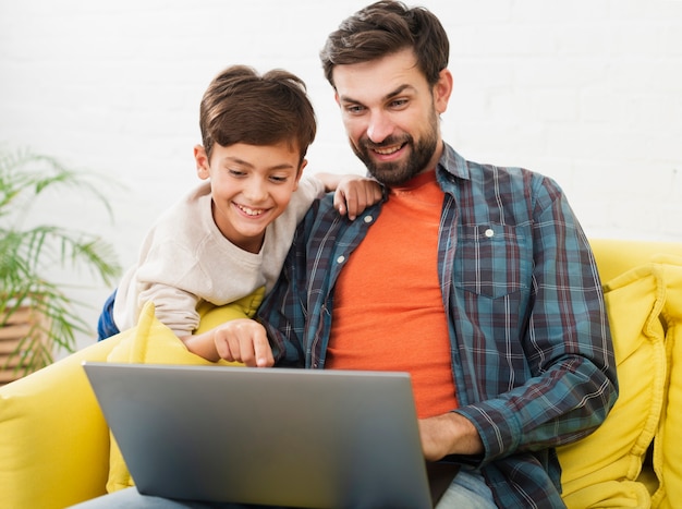 Padre e figlio felici che osservano sul computer portatile