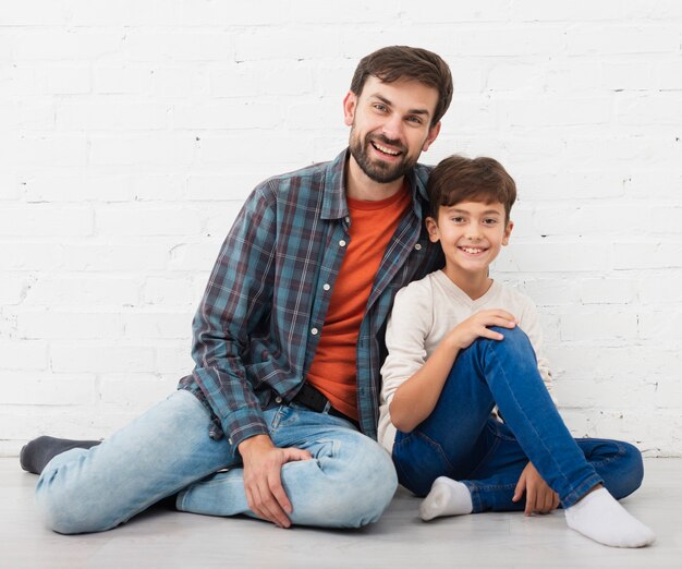 Padre e figlio felici che si siedono sul pavimento