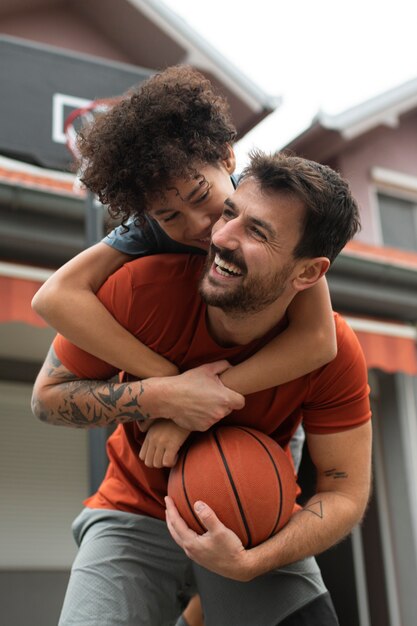 Padre e figlio giocano insieme a basket in giardino