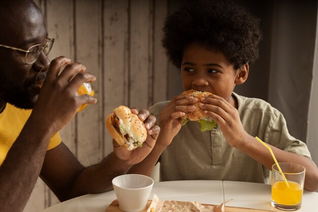 Padre e figlio pranzano insieme e si gustano hamburger e patatine fritte