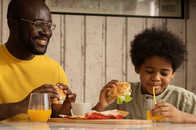 Padre e figlio pranzano insieme e si gustano hamburger e patatine fritte