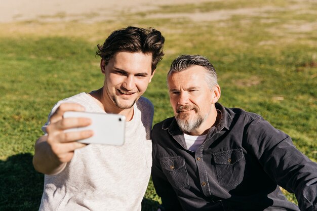 Padre e figlio prendendo selfie in spiaggia