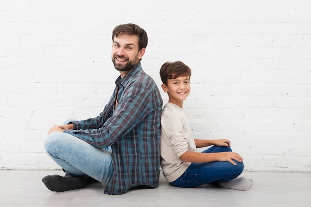 Padre e figlio seduti sul pavimento e guardando il fotografo