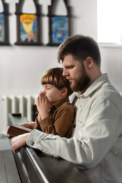 Padre e ragazzo cristiani del colpo medio in chiesa