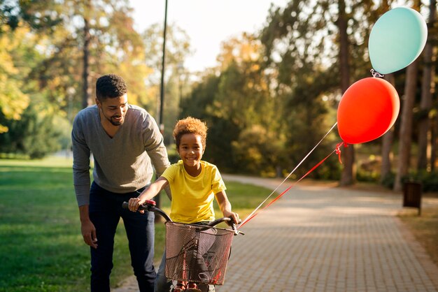 Padre felice che insegna alla sua figlia carina ad andare in bicicletta nel parco