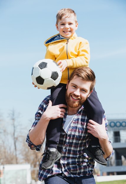 Padre felice che trasporta il suo piccolo figlio sulle spalle