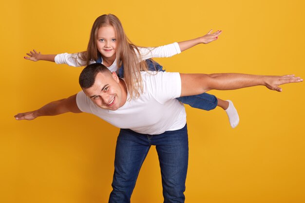 Padre felice dando a sua figlia cavalluccio, papà e figlio divertirsi insieme, famiglia felice.