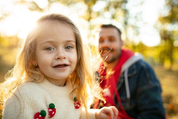 Padre felice e piccola figlia carina che camminano lungo il sentiero nel bosco in una giornata di sole autunnale