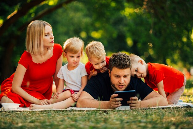 Padre giocando sul telefono e guardando i bambini