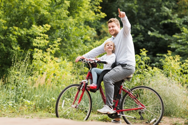 Padre in bicicletta che punta per la figlia