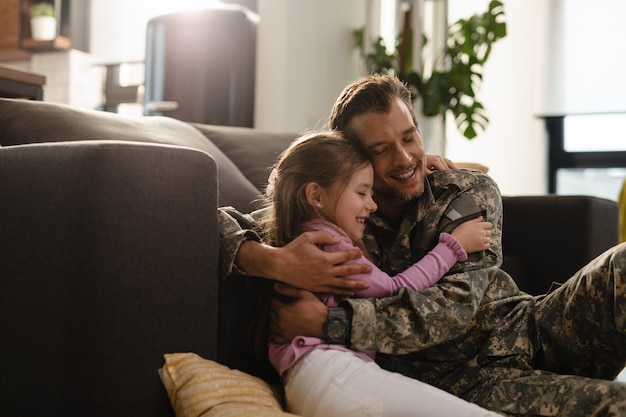 Padre militare affettuoso e sua figlia che si abbracciano con gli occhi chiusi a casa