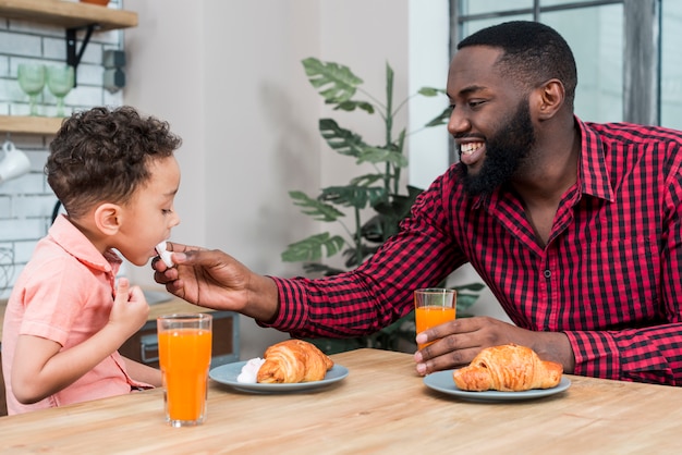 Padre nero che alimenta il figlio con i dolci