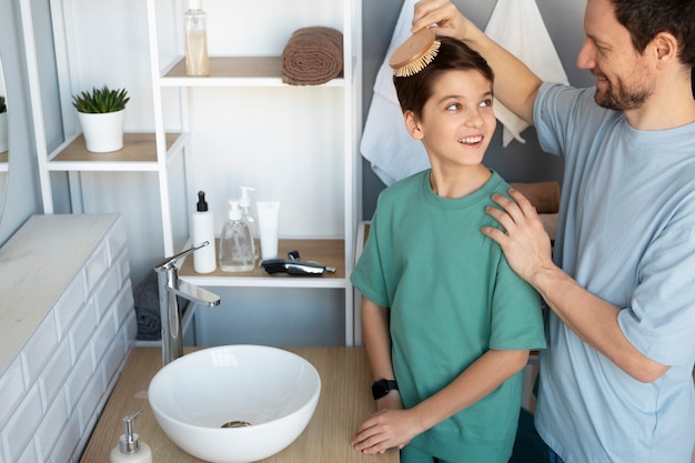 Padre sorridente ad alto angolo che spazzola i capelli del bambino