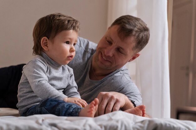 Padre sorridente del colpo medio che esamina il bambino