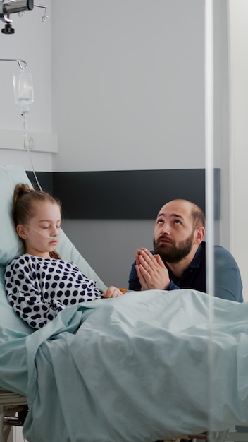 Padre triste preoccupato che si tiene per mano insieme pregando mentre aspetta la diagnosi di malattia