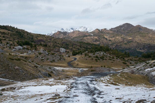 Paesaggio con molte montagne rocciose coperte di neve sotto un cielo nuvoloso