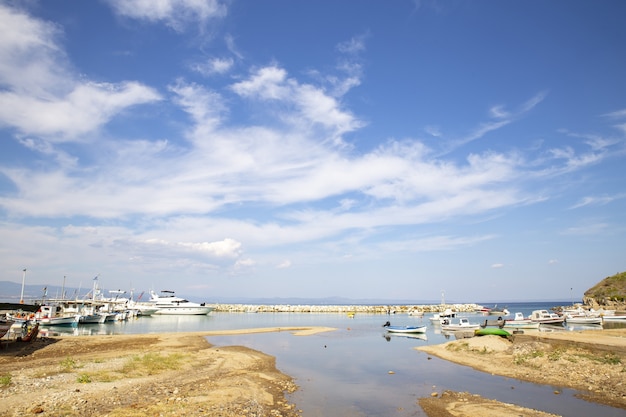 Paesaggio del mare con barche su di esso circondato da colline sotto un cielo blu