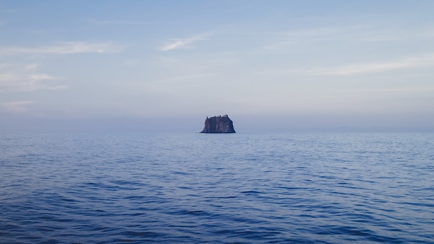 Paesaggio del mare con una roccia sotto un cielo nuvoloso durante il giorno