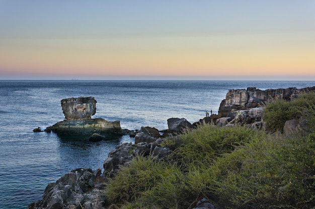 Paesaggio della gente che pesca sulle rocce delle scogliere del mare a Cascais, Portugal