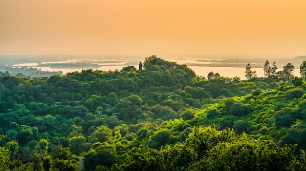 Paesaggio di colline ricoperte di verde circondate dal mare sotto un cielo nuvoloso durante il tramonto