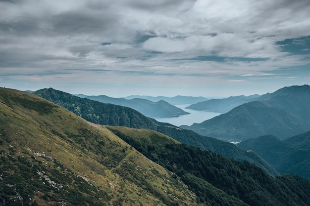 Paesaggio di colline ricoperte di verde e circondate da un fiume sotto il cielo nuvoloso