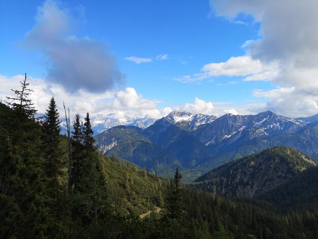 Paesaggio di colline rocciose coperte di verde sotto la luce del sole e un cielo nuvoloso blu