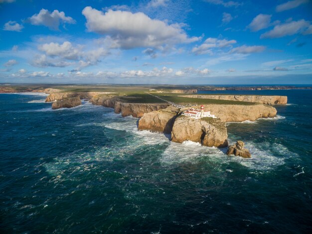 Paesaggio di colpo alto di un'isola con un palazzo su esso circondato dal mare sotto un cielo blu nel Portogallo