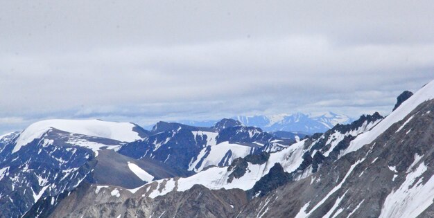 Paesaggio di montagne coperte di neve sotto un cielo nuvoloso durante il giorno