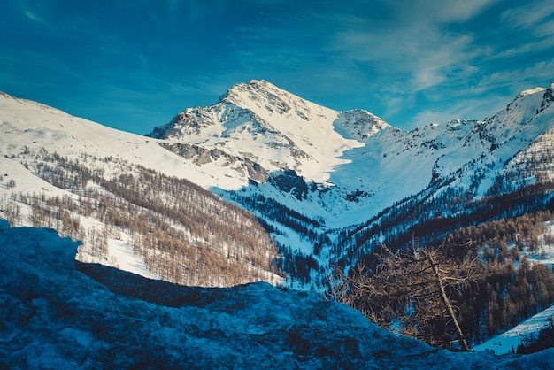 Paesaggio di montagne rocciose coperte di neve sotto la luce del sole a Sestriere in Italia