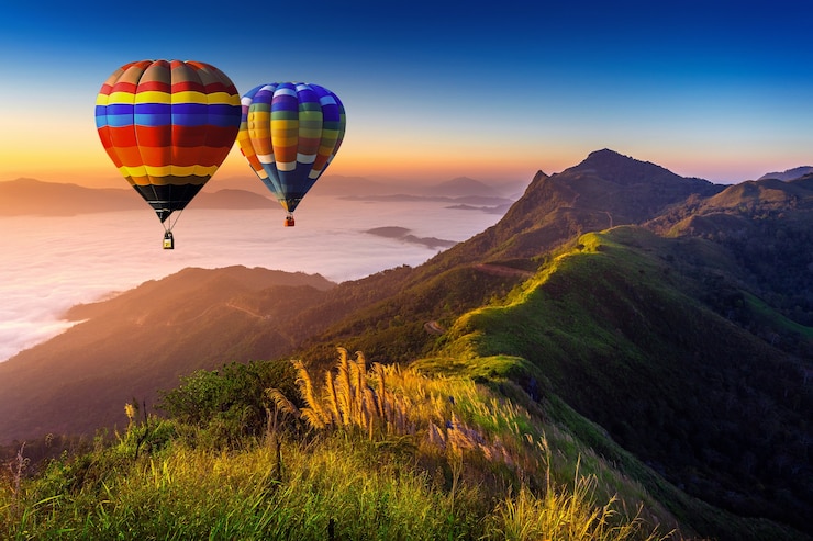 Foto gratuito paesaggio di nebbia mattutina e montagne con mongolfiere all'alba.