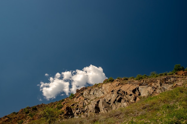 Paesaggio di rocce ricoperte di vegetazione sotto la luce del sole e un cielo blu