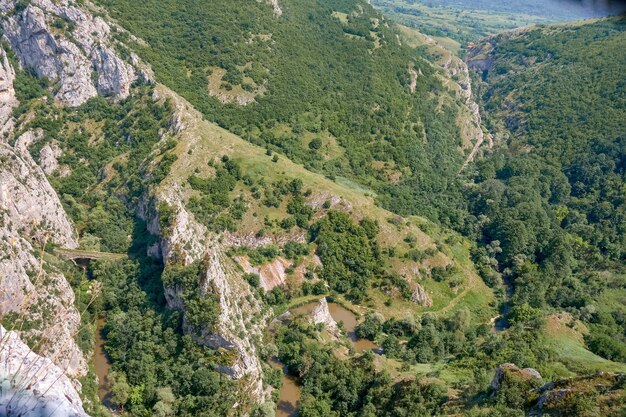 Paesaggio di rocce ricoperte di vegetazione sotto un cielo blu e la luce del sole