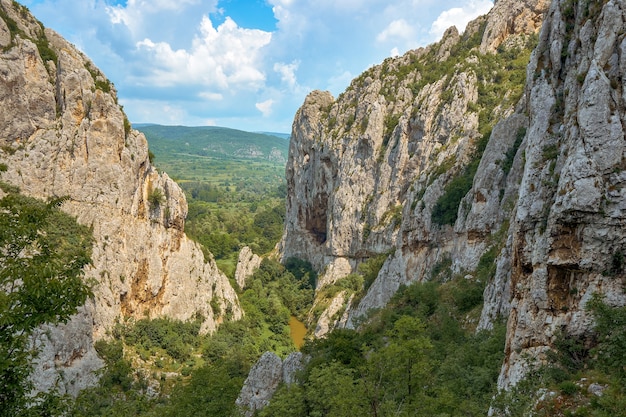 Paesaggio di rocce ricoperte di vegetazione sotto un cielo blu e luce solare