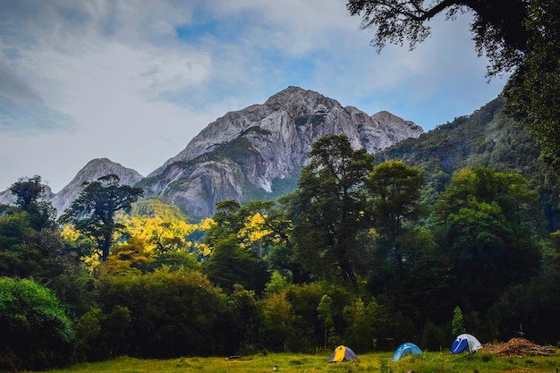 Paesaggio di un campeggio con tende su un campo circondato da colline rocciose