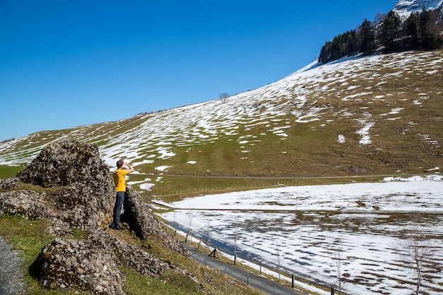 Paesaggio di un giovane in piedi tra le rocce in montagna con un po' di neve