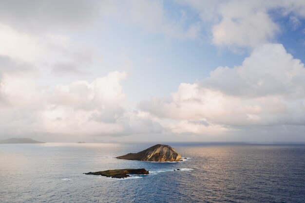 Paesaggio di una piccola isola circondata dal mare sotto un cielo nuvoloso e luce solare