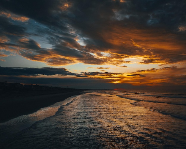 Paesaggio di una spiaggia circondata dal mare sotto la luce del sole durante una bellissima alba