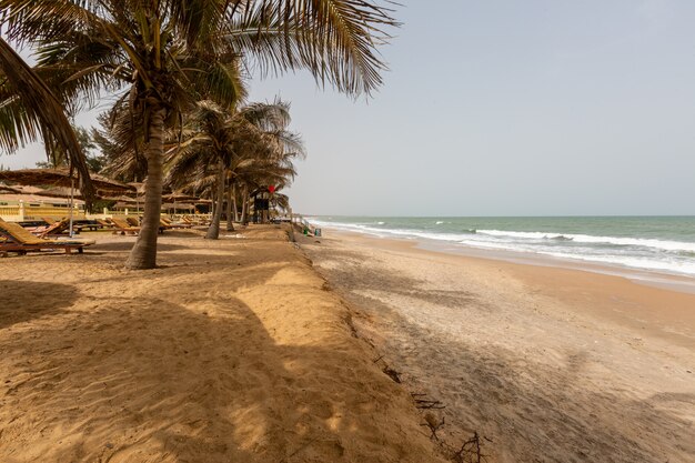 Paesaggio di una stazione balneare circondata da palme e il mare sotto un cielo blu in Gambia