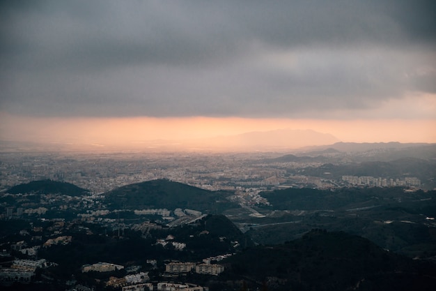 Paesaggio urbano e montagna sotto le nuvole tempestose