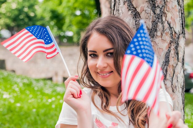 Paese, patriottismo, giorno di indipendenza e concetto di persone - felice giovane donna sorridente in abito bianco con bandiera nazionale americana