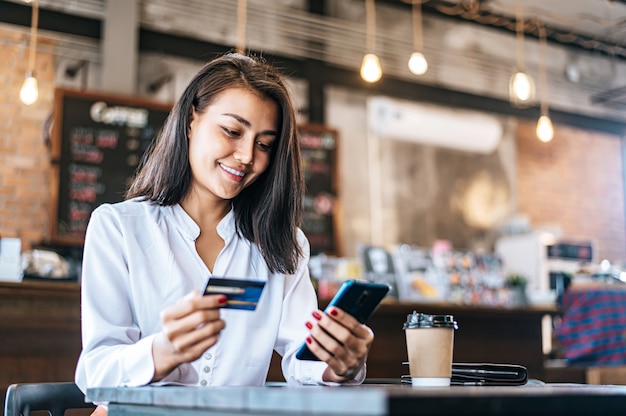 Paga le merci con carta di credito tramite uno smartphone in una caffetteria.