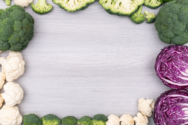 Pagina del cavolo rosso del cavolfiore variopinto dei broccoli delle verdure con lo spazio della copia su superficie di legno bianca