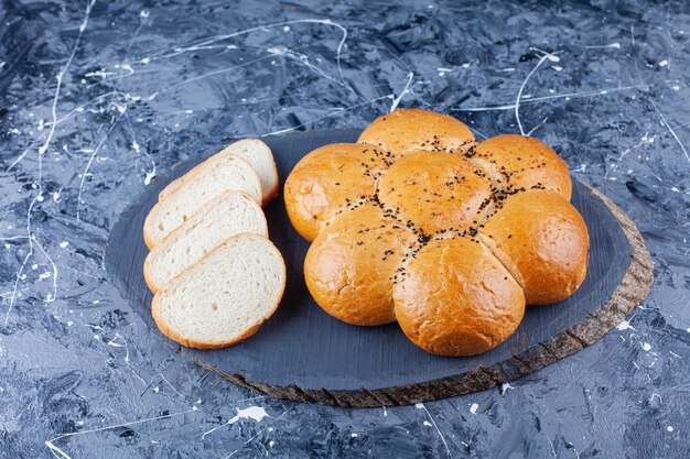 Pagnotta di pane fresco fragrante con fette di pane tostato sul tavolo blu.