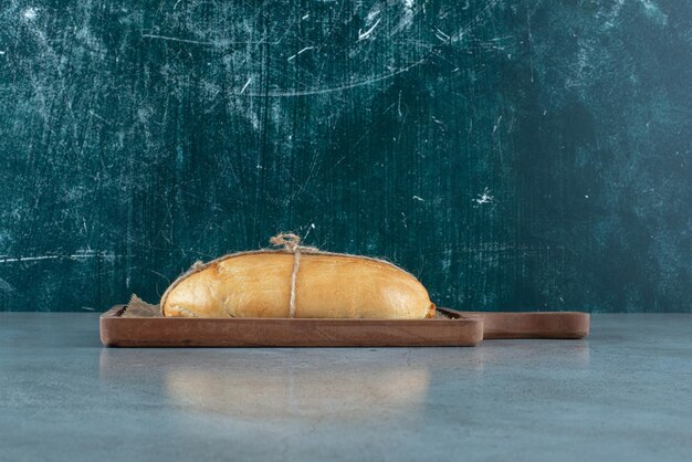 Pagnotta di pane legata con corda su tavola di legno.