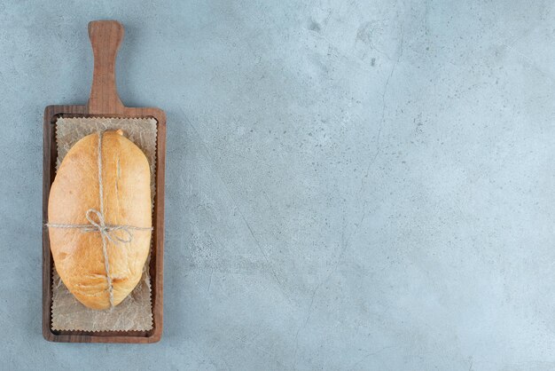 Pagnotta di pane legata con corda su tavola di legno.
