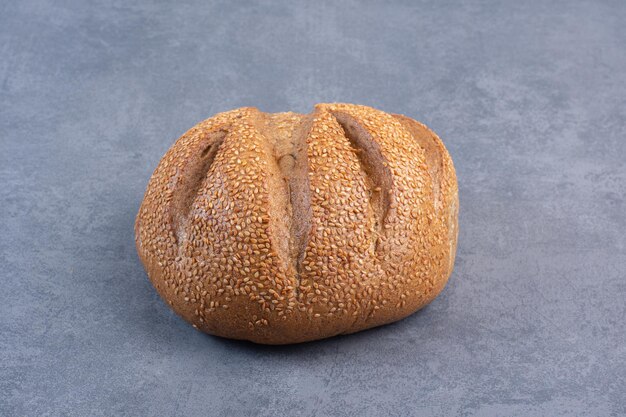 Pagnotta di pane ricoperta di semi di sesamo su fondo marmo. Foto di alta qualità