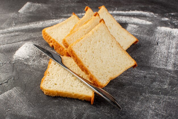 Pagnotte di pane bianco vista frontale affettate e gustose isolate con coltello su grigio