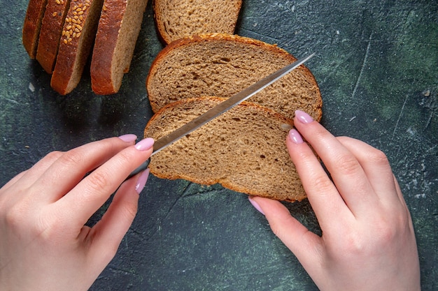 Pagnotte di pane scuro vista dall'alto con taglio femminile sulla scrivania scura