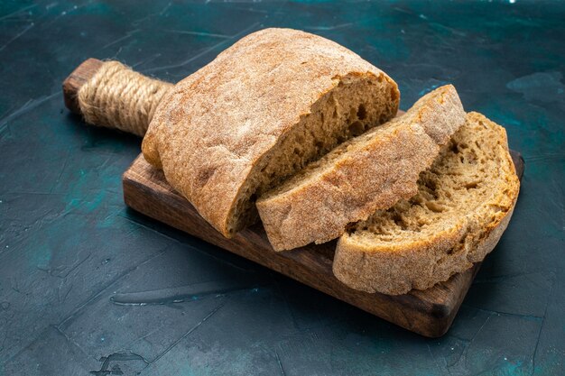 Pagnotte di pane vista frontale gustose cotte sulla scrivania blu scuro.